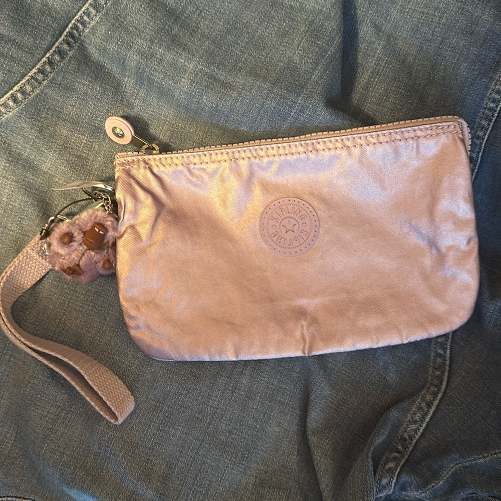 Kipling metallic lilac pouch 5”x8.5”; new. Interior zipper pocket, wrist strap